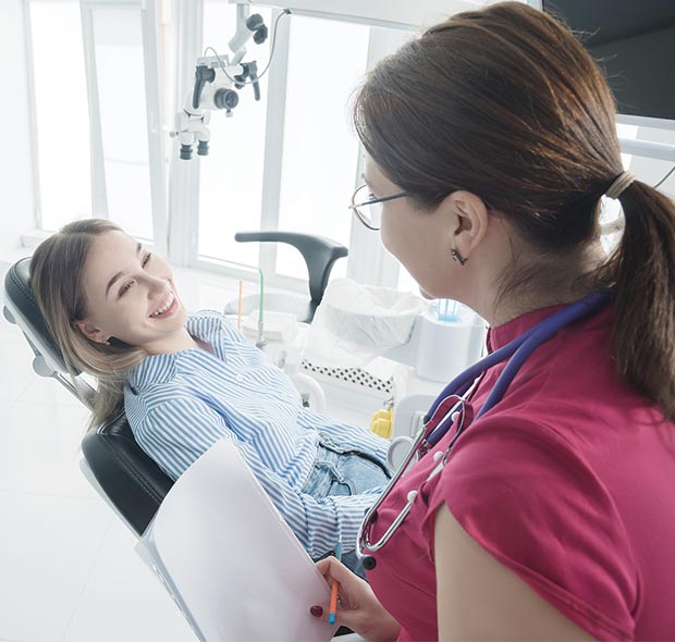 Teen smiling with braces during orthodontic treatment session.