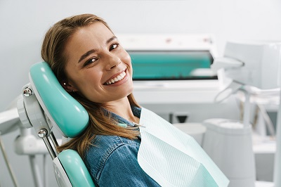 European young woman smiling while sitting in medical chair at d